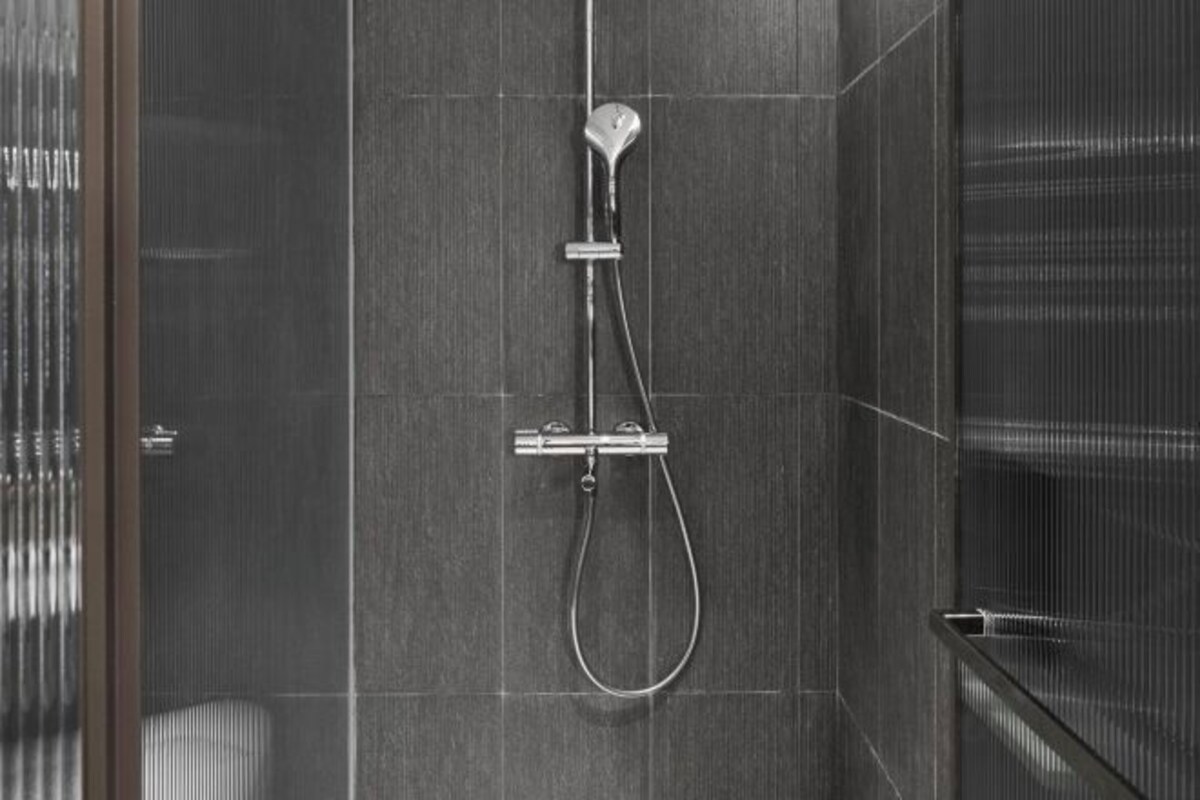 A modern shower with a handheld showerhead and a fixed rain showerhead mounted on the wall.