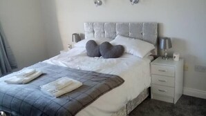 A neatly made bed with a grey and white duvet, a grey headboard, and a bedside table with a lamp. - Entire House, Self Catering in Castlerea Ireland (Castlerea)