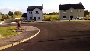A residential street with two houses, a roundabout, and a white van parked on the side. - Entire House, Self Catering in Castlerea Ireland (Castlerea)