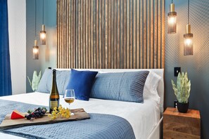A bedroom with a bed, bedside tables, a wine bottle, and a fruit platter. - Hidden Oasis With Private Pool - Near FQ (New Orleans)