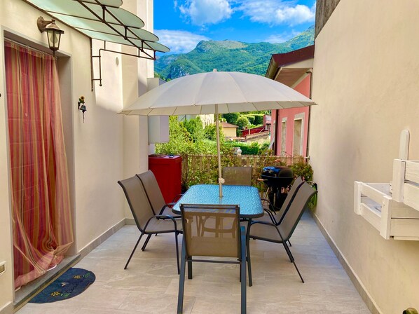 A small patio with a table and chairs, a red cabinet, and a grill. - Casa La Wanda - Camaiore, Toscana - 2 Br & Terrace (Camaiore Lucca)