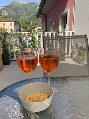 Two glasses of amber liquid on a glass table with a bowl of donuts. - Casa La Wanda - Camaiore, Toscana - 2 Br & Terrace (Camaiore Lucca)