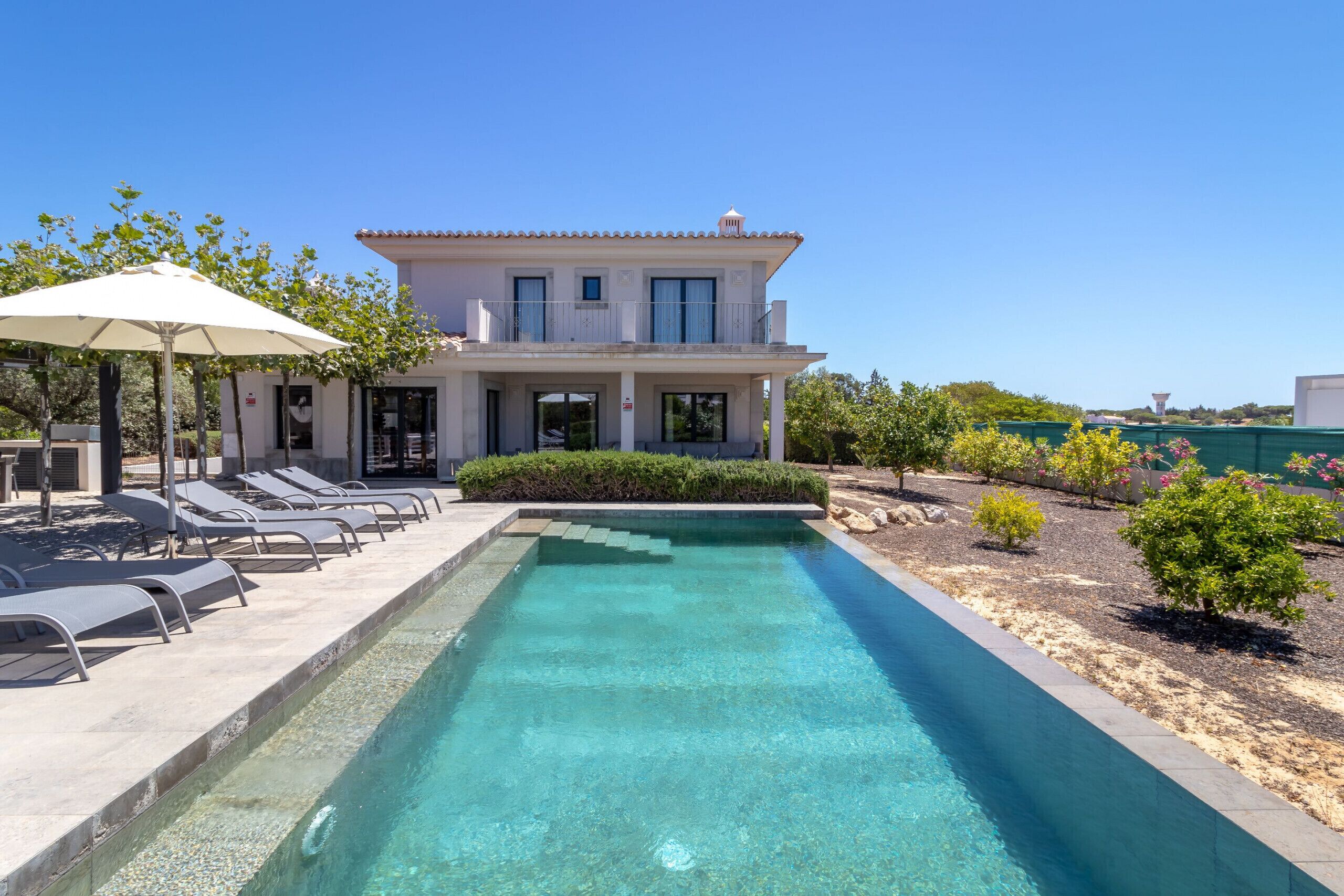 A poolside area with lounge chairs and a clear pool.