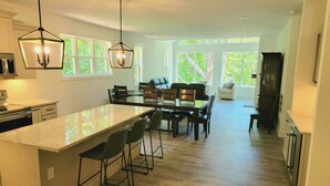 A spacious kitchen with a large island, wooden flooring, and pendant lighting.