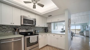 Una cocina moderna con armarios blancos, electrodomésticos de acero inoxidable y salpicadero de azulejos.