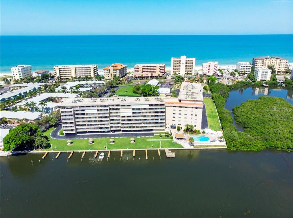 An aerial view of a hotel with multiple buildings, a marina, and a beach in the background.