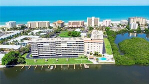 Vista aérea de un hotel con varias edificaciones, un puerto deportivo y una playa al fondo.