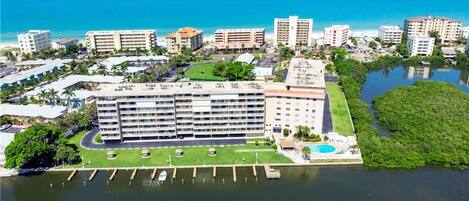 An aerial view of a hotel with multiple buildings, a marina, and a beach in the background.