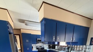 Eine moderne Küche mit blauen Schränken, einem Edelstahl-Kühlschrank, einem Einbauofen und einer Marmorarbeitsplatte.