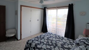 A bedroom with a bed, a ceiling fan, a wardrobe, a chair, and a window with curtains. - 37 Brady Street Mallacoota (Mallacoota)