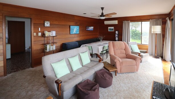 A cozy living room with a sofa, armchair, and a dining table. - 37 Brady Street Mallacoota (Mallacoota)