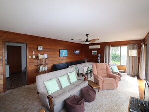 A cozy living room with a sofa, armchair, and a dining table.