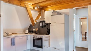 Une cuisine de taille réduite, avec des meubles blancs, une cuisinière et un évier.