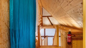 Un escalier en bois mène à un balcon où est fixé un extincteur au mur.