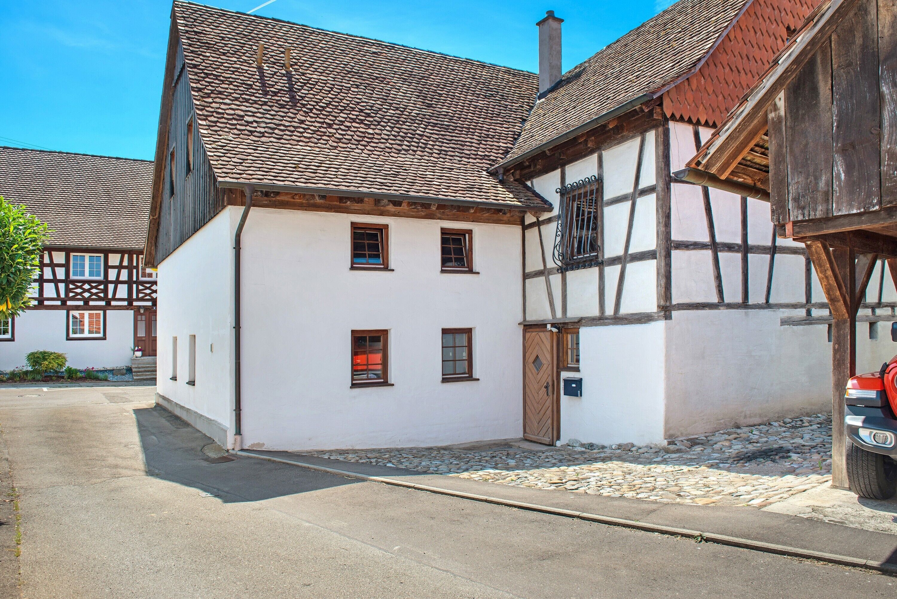 Une maison traditionnelle à colombages, dotée d’une façade blanche et d’un toit à forte pente.