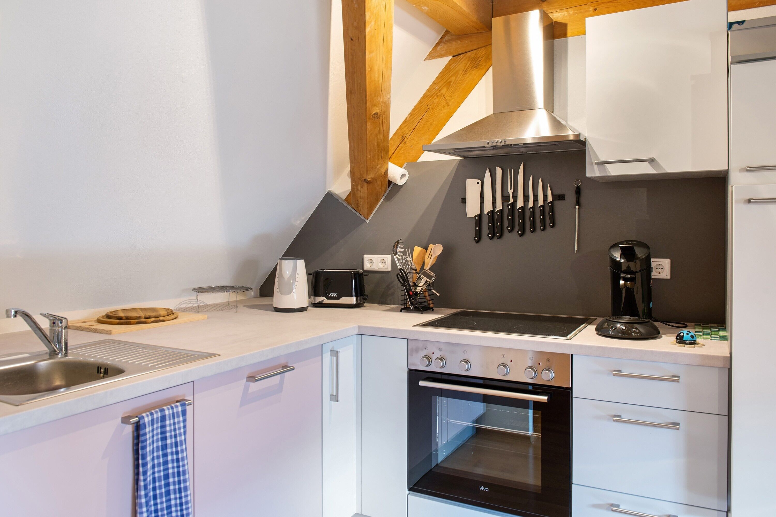 Une cuisine moderne équipée d’un évier, d’une cuisinière, d’un four et d’un ensemble de couteaux accrochés au mur.