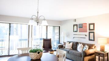 A modern living room with a round dining table, a sofa, and a chandelier.