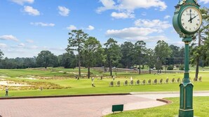 A golf course with a Rolex clock, trees, and a clear sky. - Newly Renovated Property. (Pinehurst)