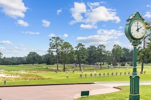 Un parcours de golf avec une horloge Rolex, des arbres et un ciel dégagé.
