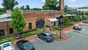 A brick building with a large arched entrance, surrounded by a parking lot and greenery. - Newly Renovated Property. (Pinehurst)