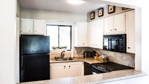 A kitchen with white cabinets, a black refrigerator, a microwave, and a stove. - Newly Renovated Property. (Pinehurst)