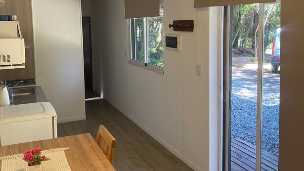 Une cuisine moderne dotée d’une cuisinière intégrée et d’un coin repas avec une table et des chaises en bois.