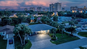 A residential area with a house featuring a paved driveway, surrounded by palm trees and a well-maintained lawn. - Elegant 4BR Pool Home + Guest House | Walk to Beach (Naples)
