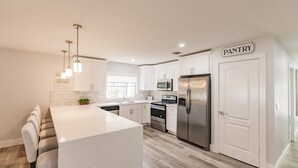 A modern kitchen with white cabinets, stainless steel appliances, and a central island. - Serenity by the Sea: Heated Pool, Bikes & Coastal Charm (Naples)