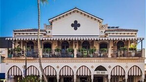 A building with a central atrium, multiple balconies, and a palm tree in the foreground. - Spacious 2-Story Villa with Pool & Putting Green (Naples)