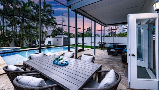 A covered patio with a pool, wicker furniture, and a view of the sky. - Spacious 2-Story Villa with Pool & Putting Green (Naples)