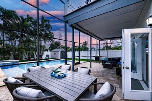 A covered patio with a pool, wicker furniture, and a view of the sky.