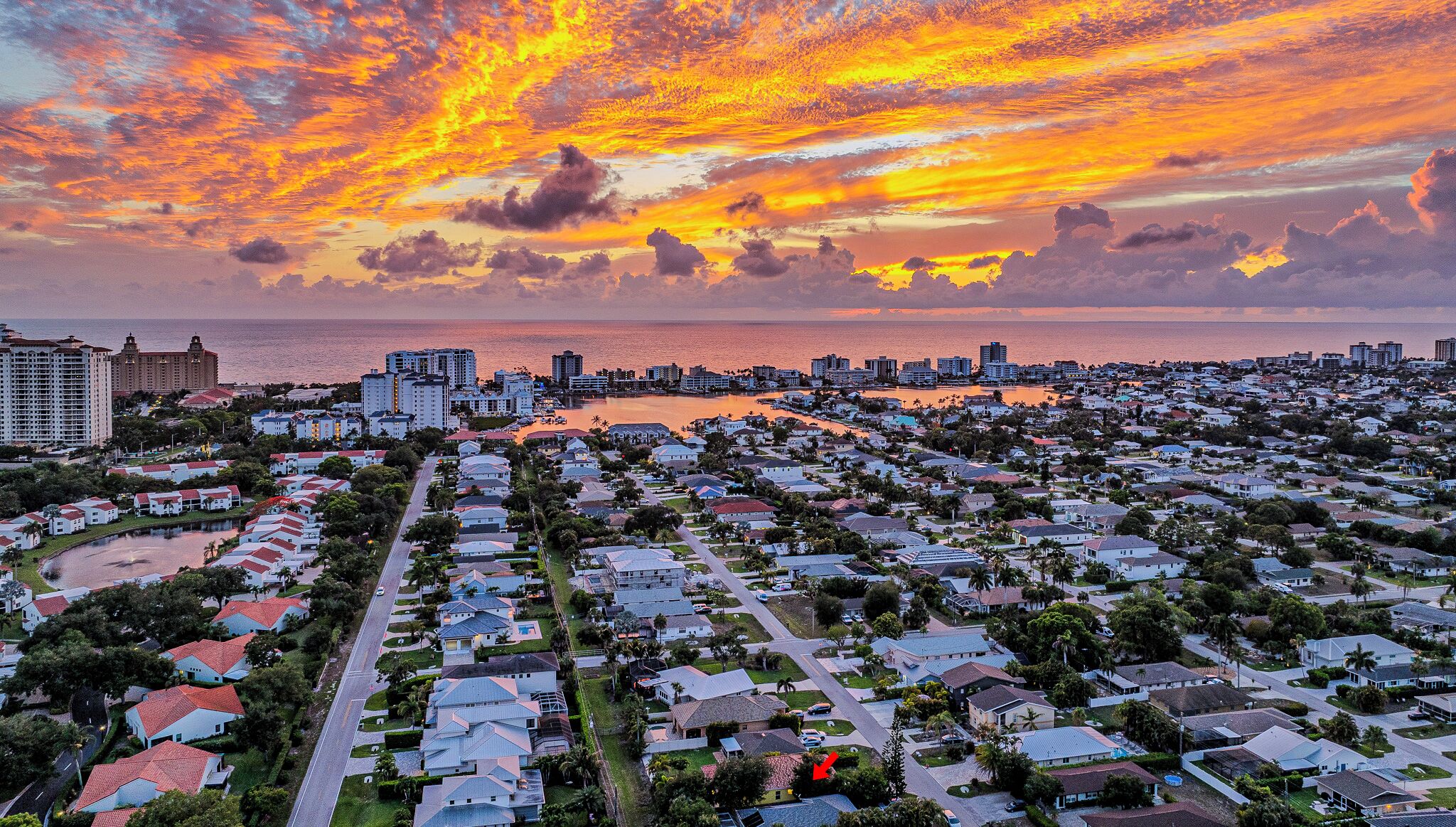 A coastal residential area with a sunset view, featuring a mix of single-family homes and high-rise buildings.