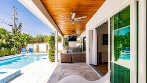 Et overdækket udendørsområde med pool, liggestole og ventilator.