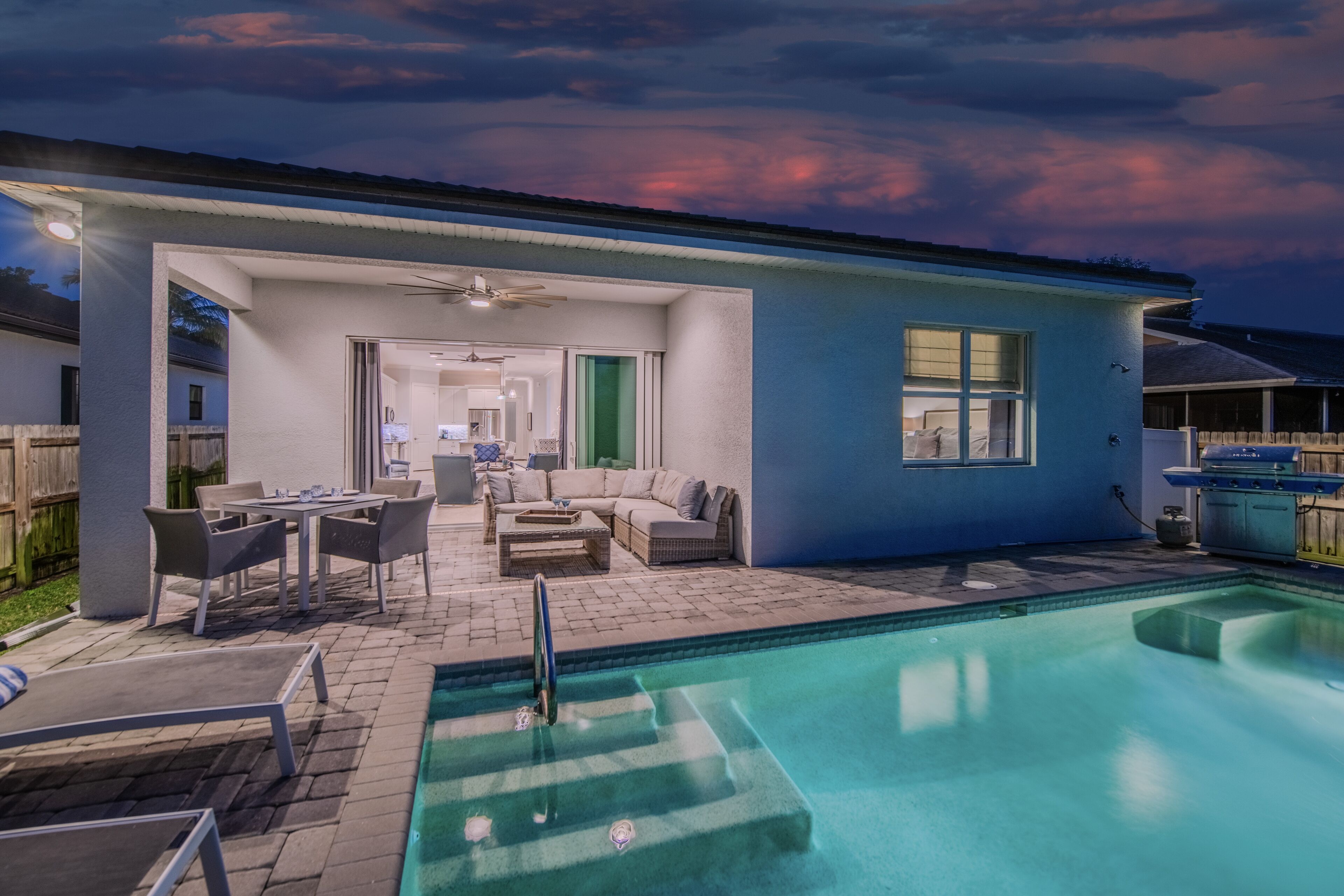 A modern house with a swimming pool, outdoor seating, and a patio area.