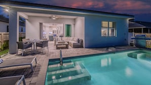 A modern house with a swimming pool, outdoor seating, and a patio area. - Casa Allegra | Bright, Modern 4 BR Pool Home in Naples Park (Naples)