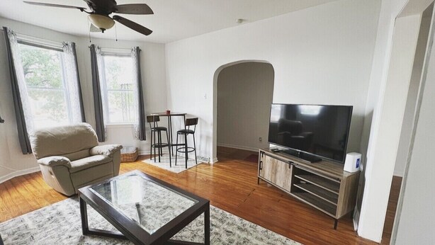 Ein Wohnzimmer mit Sofa, Couchtisch, Fernseher und Deckenventilator.