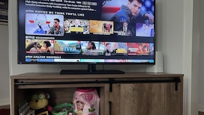 Ein Fernseher zeigt ein Menü zur Filmauswahl mit Kategorien wie 'Top Gun' und 'Filme, die Ihnen gefallen könnten'.