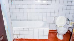 Een badkamer met witte betegelde wanden, een wit bad en een wit toilet.