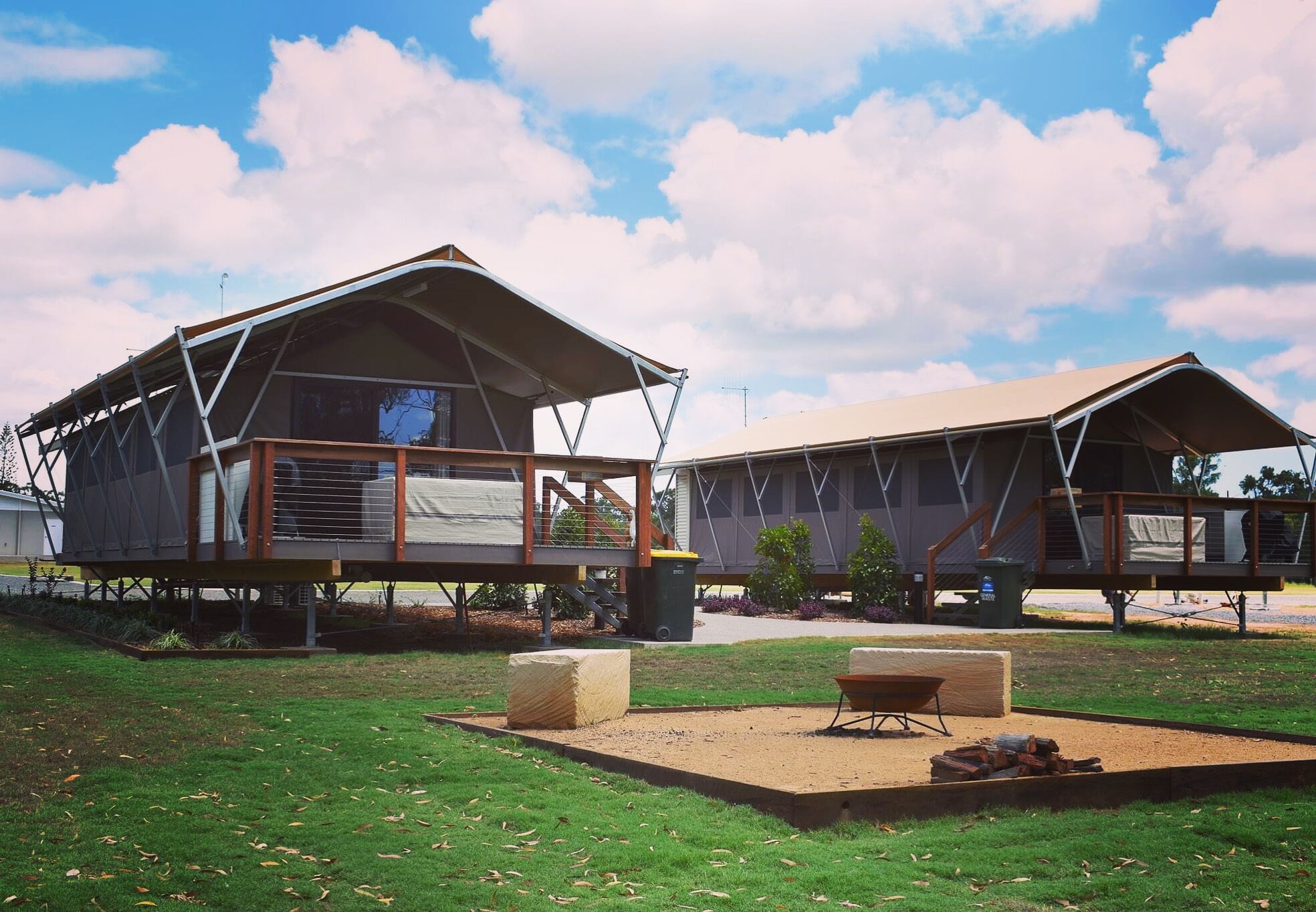 Two modern, spacious cabins with large windows, outdoor seating, and a fire pit in the yard.