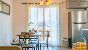 A kitchen with a stainless steel refrigerator, a dining table with chairs, and a view of mountains through the window. - New 20% discount - Backyard PARADISE - JT Escape w/ Hot Tub (Joshua Tree)