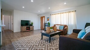 A living room with a TV, two sofas, a coffee table, and a patterned rug. - New 20% discount - Backyard PARADISE - JT Escape w/ Hot Tub (Joshua Tree)