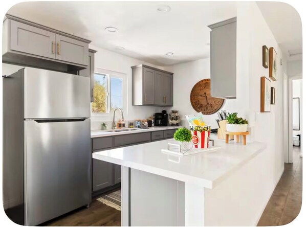 A modern kitchen with a central island, stainless steel appliances, and a large wall clock.