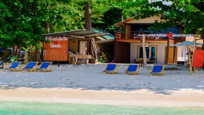 Un hotel frente a la playa con una zona de estar techada y un cartel que dice "LIFE GARDEN BEACH RESORT".