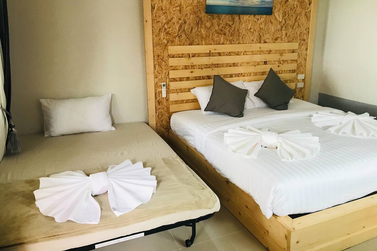 Two single beds with wooden headboards, white bedding, and towels arranged on the beds.