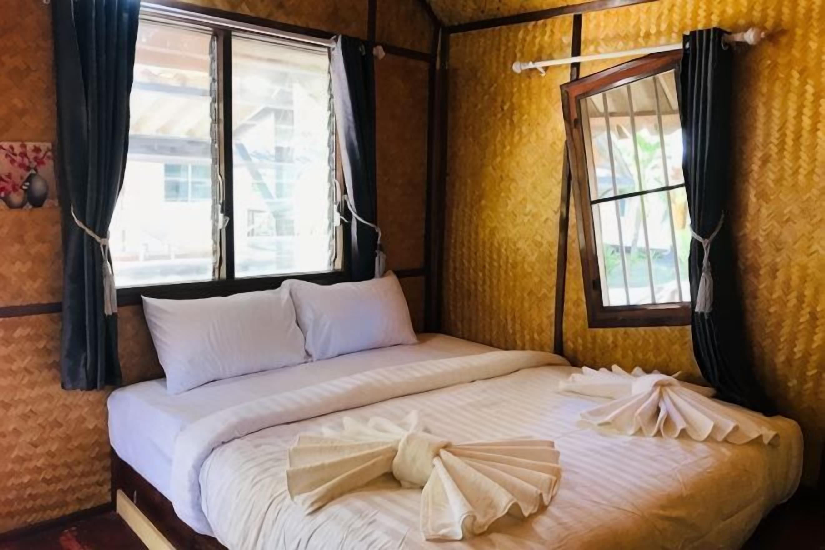 A room with a bed, two windows, and a curtain.