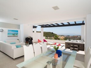 Uma sala de estar moderna com um sofá, uma mesa de jantar e vista para a paisagem.