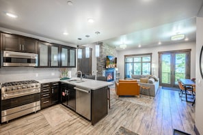 A modern kitchen with stainless steel appliances, a large island, and a fireplace.