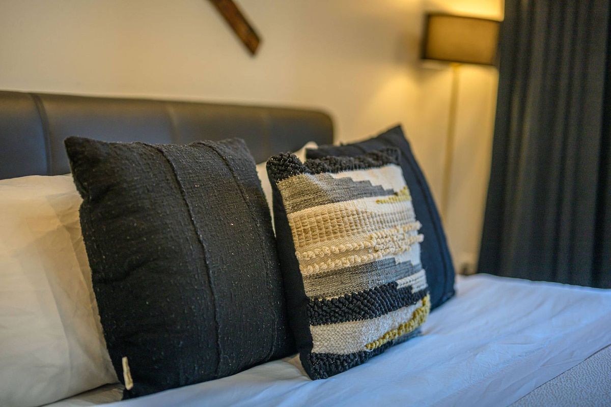 A bed with two pillows, one plain and one with a striped pattern.