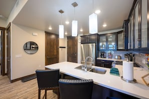 A modern kitchen with a central island, stainless steel appliances, and pendant lighting.