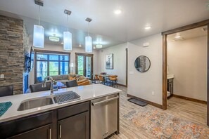 A modern kitchen with a built-in dishwasher, pendant lighting, and a stone accent wall.